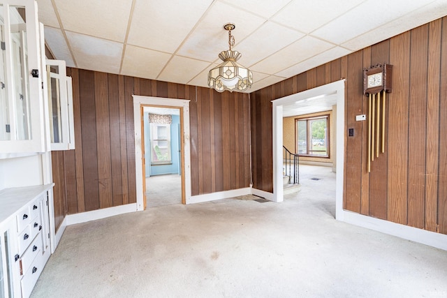 244 N Miami St, Wabash, IN 46992 - unfurnished dining area with wood walls, a paneled ceiling, baseboards, a chandelier, and light carpet