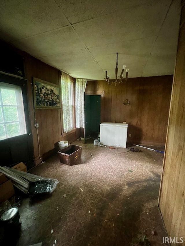 718 E Lewis St, Fort Wayne, IN 46802 - unfurnished living room featuring wooden walls and a chandelier