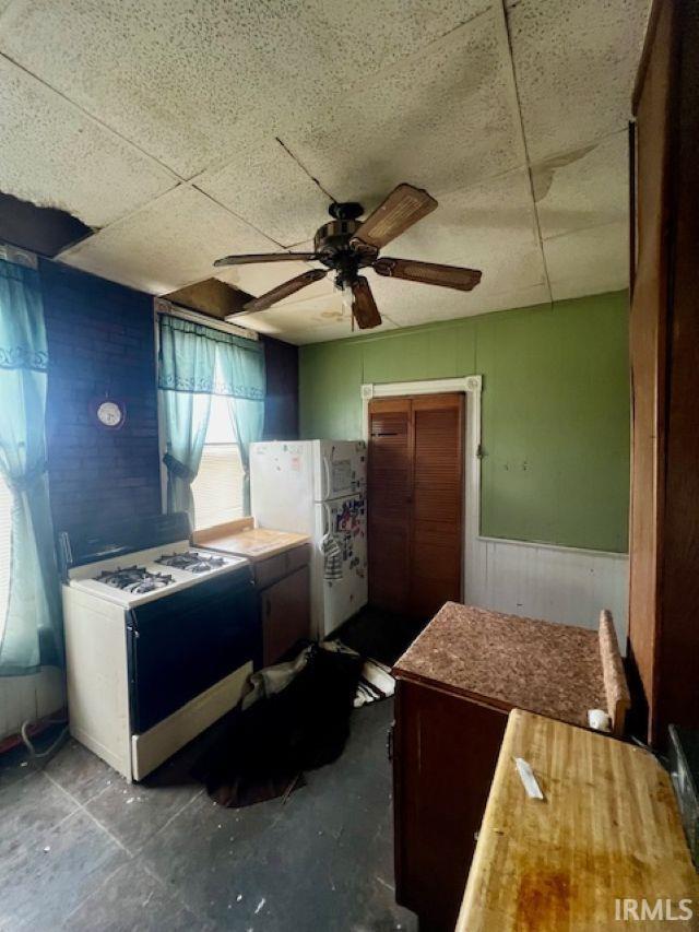 718 E Lewis St, Fort Wayne, IN 46802 - kitchen featuring white appliances, ceiling fan, a wainscoted wall, a drop ceiling, and wood walls