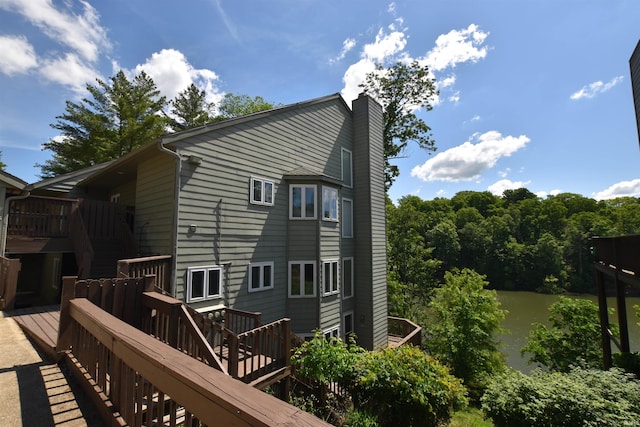 9763 S Harbour Pointe Dr Unit 34, Bloomington, IN 47401 - view of property exterior featuring stairs, a chimney, and a deck with water view