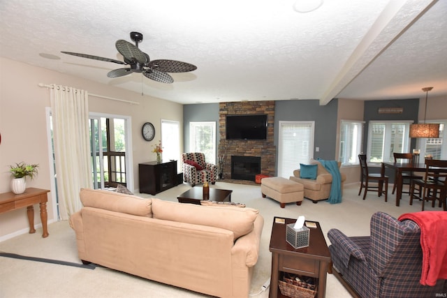 9763 S Harbour Pointe Dr Unit 34, Bloomington, IN 47401 - living room with a textured ceiling, carpet, ceiling fan, a stone fireplace, and baseboards