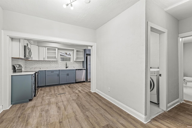 809 S Logan St, South Bend, IN 46615 - kitchen with appliances with stainless steel finishes, washer / dryer, light wood-style floors, light countertops, and decorative backsplash