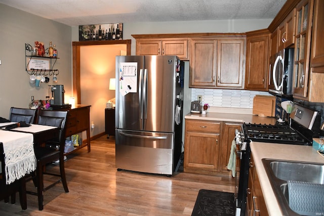 2329 Glenwood Ave, Fort Wayne, IN 46805 - kitchen featuring stainless steel appliances, light wood-style flooring, light countertops, decorative backsplash, and brown cabinets
