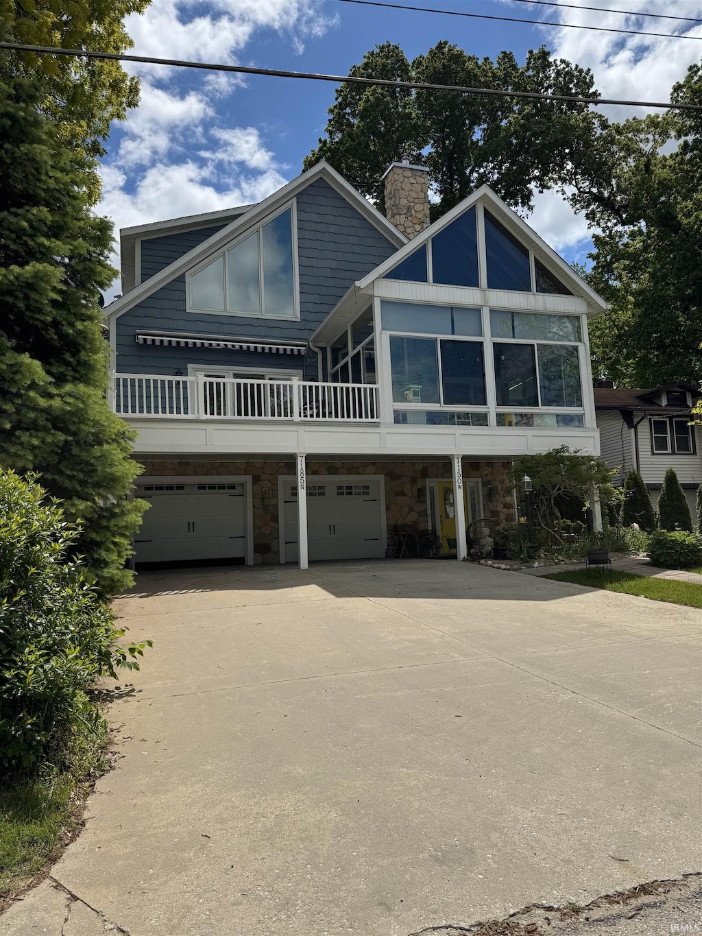 7185 N 1150 W, Shipshewana, IN 46565 - view of front facade featuring a garage, stone siding, a chimney, and concrete driveway