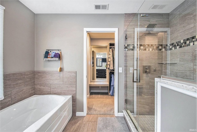 54453 Sagewood Dr, Mishawaka, IN 46545 - bathroom featuring a stall shower, a spacious closet, a garden tub, and wood finished floors