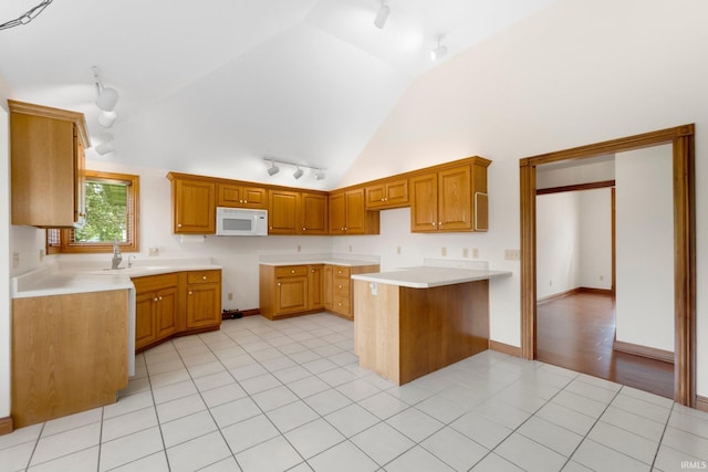 2519 Knightsbridge Dr, Fort Wayne, IN 46815 - kitchen featuring track lighting, white microwave, vaulted ceiling, a sink, and brown cabinets