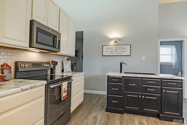 853 S 400 E Rd, Marion, IN 46953 - kitchen featuring appliances with stainless steel finishes, dark cabinets, light wood-style flooring, decorative backsplash, and baseboards