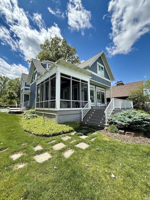 6138 E Elwood St, Syracuse, IN 46567 - back of house featuring a sunroom, a lawn, a shingled roof, and stairway
