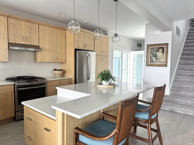 6138 E Elwood St, Syracuse, IN 46567 - kitchen with appliances with stainless steel finishes, under cabinet range hood, a kitchen bar, light brown cabinetry, and a center island