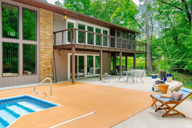 4691 E Inverness Woods Rd, Bloomington, IN 47401 - back of house with stone siding, a patio, board and batten siding, outdoor dining space, and a balcony