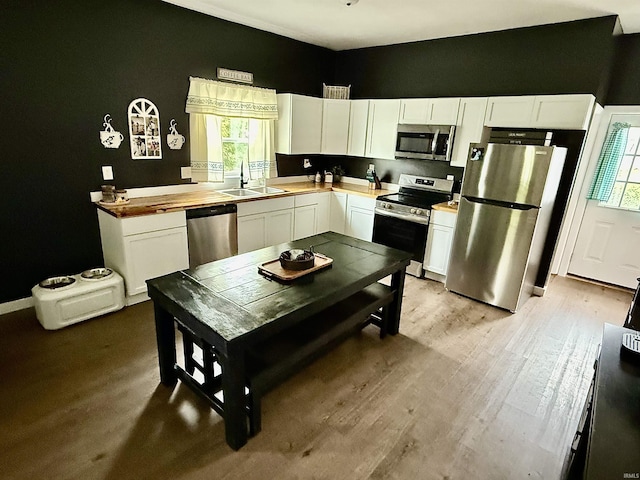 302 L St, Bedford, IN 47421 - kitchen with appliances with stainless steel finishes, a sink, white cabinets, and light wood-type flooring