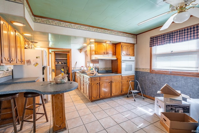 139 Elm St, Wabash, IN 46992 - kitchen with white oven, under cabinet range hood, ceiling fan, a peninsula, and a kitchen breakfast bar