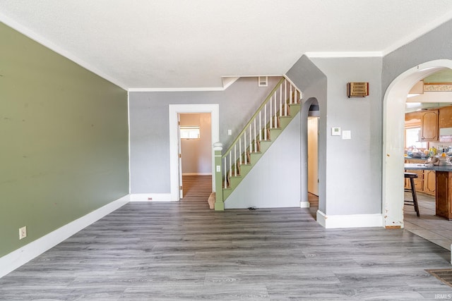 139 Elm St, Wabash, IN 46992 - unfurnished living room with arched walkways, wood finished floors, stairs, baseboards, and crown molding