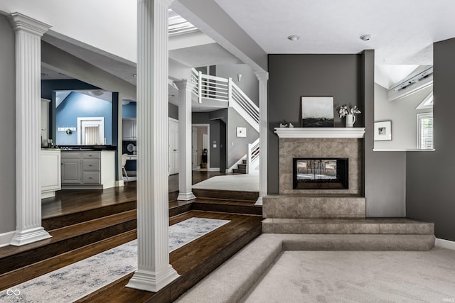 10919 Running Tide Ct, Indianapolis, IN 46236 - living room featuring ornate columns, dark wood-style flooring, stairway, a multi sided fireplace, and baseboards