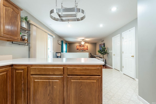 687 N Deer Lake Dr, Bloomfield, IN 47424 - kitchen with light flooring, a peninsula, brown cabinetry, light countertops, and baseboards