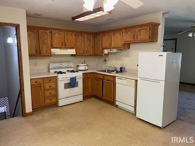 56862 Pomona St, Elkhart, IN 46516 - kitchen with white appliances, under cabinet range hood, ceiling fan, brown cabinetry, and light countertops