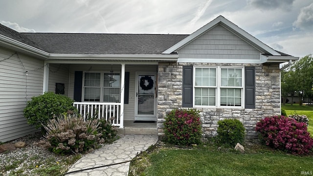 1237 Northstone Rd, Goshen, IN 46526 - view of exterior entry featuring a porch, stone siding, a shingled roof, and a lawn