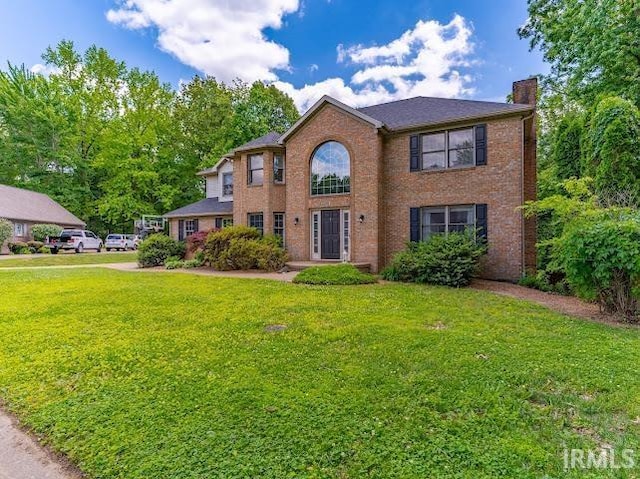237 Knollview Dr, Evansville, IN 47711 - colonial house featuring a chimney, a front lawn, and brick siding