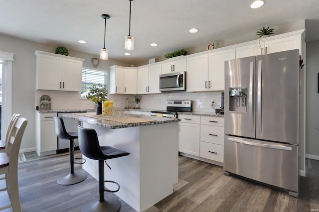 606 W Elm St, Haubstadt, IN 47639 - kitchen with appliances with stainless steel finishes, decorative backsplash, a breakfast bar, white cabinets, and wood finished floors