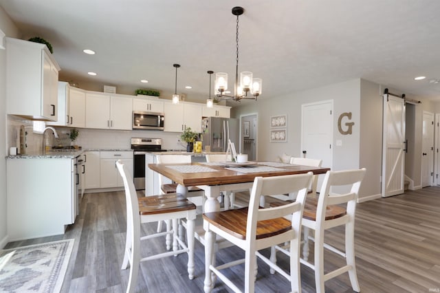 606 W Elm St, Haubstadt, IN 47639 - dining room with a barn door, wood finished floors, recessed lighting, a chandelier, and baseboards