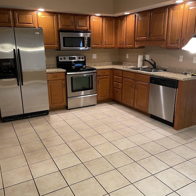 1841 S Patriot Dr, Yorktown, IN 47396 - kitchen featuring stainless steel appliances, a sink, light tile patterned floors, brown cabinetry, and light countertops