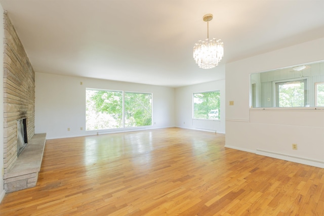 16128 Chandler Blvd, Mishawaka, IN 46544 - unfurnished living room featuring light wood-type flooring, a chandelier, a brick fireplace, baseboard heating, and baseboards