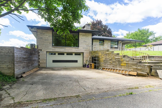 16128 Chandler Blvd, Mishawaka, IN 46544 - view of front of house with stairway, stone siding, driveway, an attached garage, and a chimney