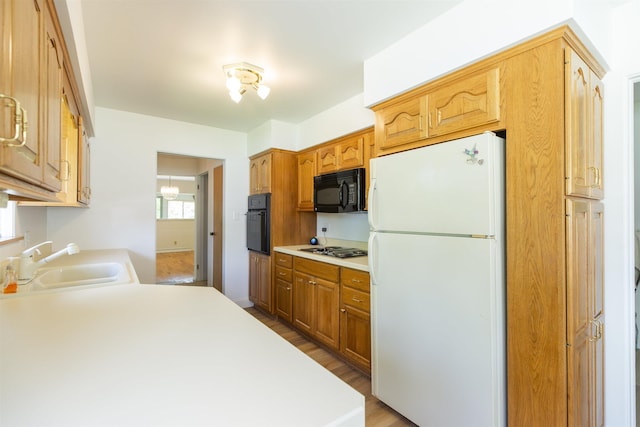 16128 Chandler Blvd, Mishawaka, IN 46544 - kitchen with black appliances, a sink, light wood-style flooring, and light countertops