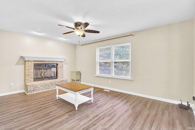 325 W Persimmon Ct, Bloomington, IN 47403 - unfurnished living room with ceiling fan, wood finished floors, a brick fireplace, and baseboards