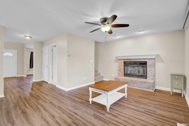325 W Persimmon Ct, Bloomington, IN 47403 - unfurnished living room with ceiling fan, a brick fireplace, wood finished floors, stairway, and baseboards