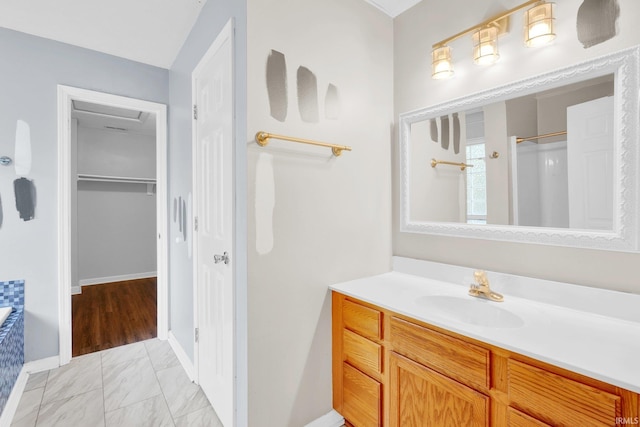 325 W Persimmon Ct, Bloomington, IN 47403 - bathroom featuring vanity, marble look tiles, a shower, a walk in closet, and baseboards