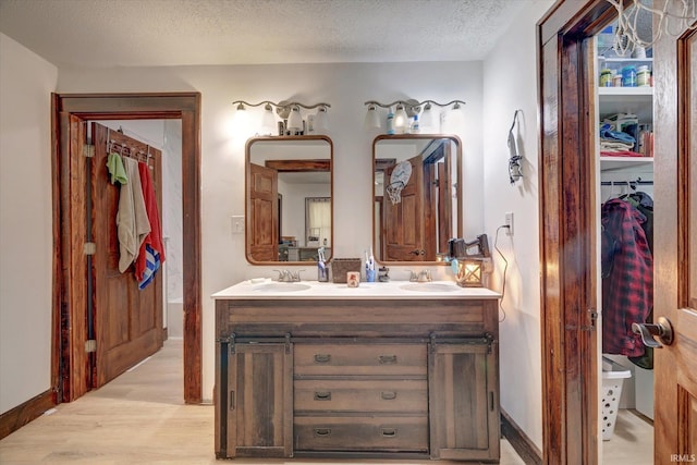 408 S Sale St, Ellettsville, IN 47429 - full bath with double vanity, wood finished floors, a spacious closet, a textured ceiling, and baseboards