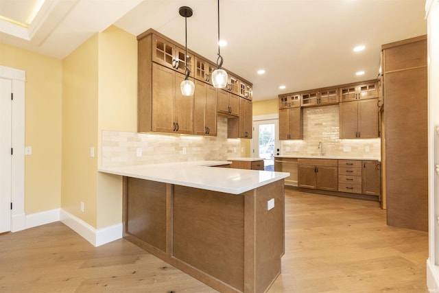 324 W Mishawaka Ave, Mishawaka, IN 46545 - kitchen featuring a peninsula, light wood-style floors, glass insert cabinets, decorative backsplash, and brown cabinetry