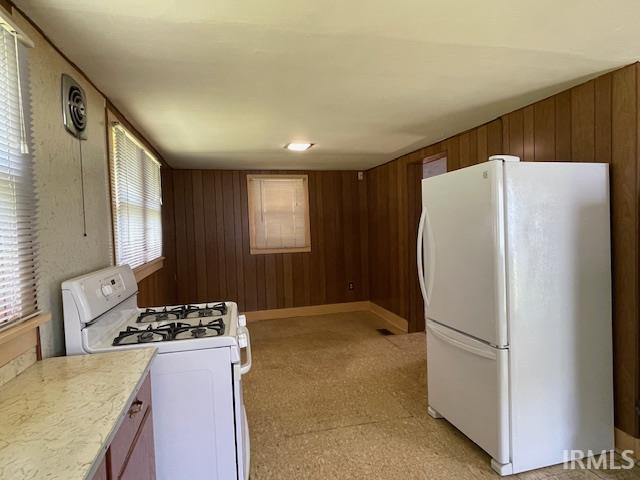 1242 Edwin St, Huntington, IN 46750 - kitchen with white appliances, wood walls, light countertops, light carpet, and brown cabinets