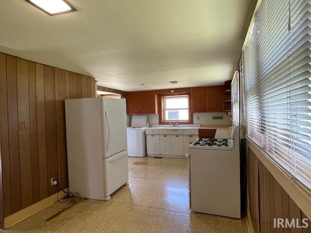 1242 Edwin St, Huntington, IN 46750 - kitchen featuring white appliances, light flooring, wood walls, washer / clothes dryer, and light countertops
