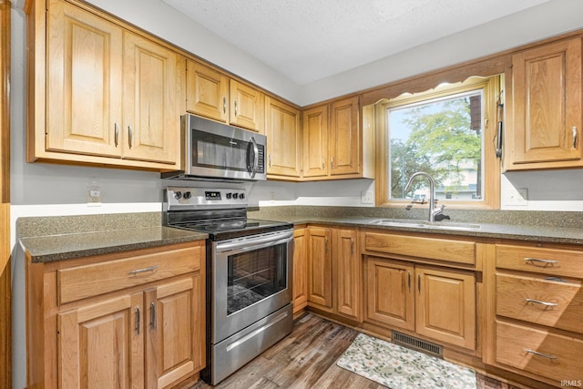 5318 Bedrock Ct, Fort Wayne, IN 46825 - kitchen featuring stainless steel appliances, a sink, wood finished floors, and dark stone countertops