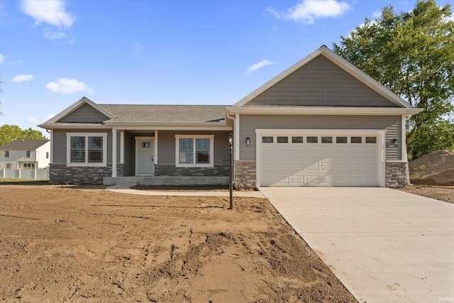 1409 Wilderness Trl, Osceola, IN 46561 - view of front of house featuring a garage, driveway, stone siding, and covered porch