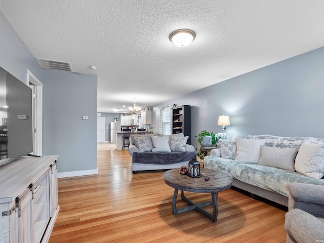 1346 Grayston Ave, Huntington, IN 46750 - living room with a chandelier, light wood-style flooring, a textured ceiling, and baseboards