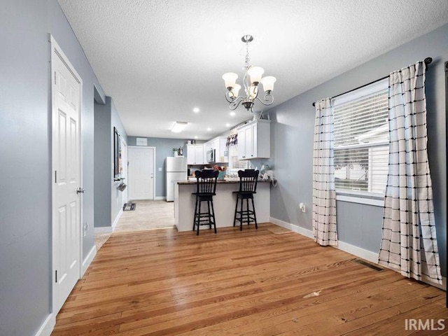1346 Grayston Ave, Huntington, IN 46750 - kitchen with freestanding refrigerator, light wood finished floors, a chandelier, a peninsula, and baseboards