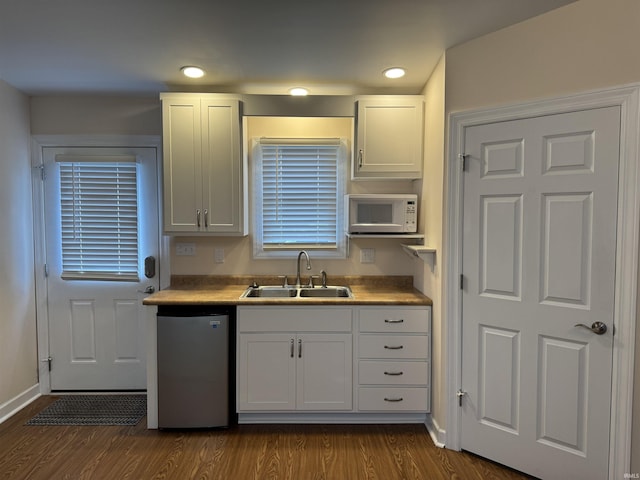 2109 Ball Ct, Rochester, IN 46975 - kitchen featuring dishwasher, a sink, white microwave, dark wood-type flooring, and white cabinetry