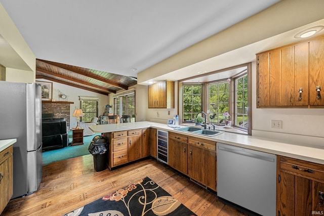 21485 Wallen Dr, South Bend, IN 46628 - kitchen with dishwashing machine, freestanding refrigerator, a sink, vaulted ceiling, and wood-type flooring