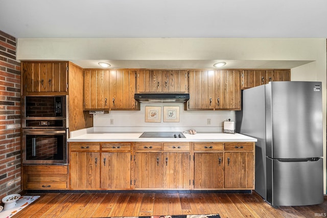 21485 Wallen Dr, South Bend, IN 46628 - kitchen with appliances with stainless steel finishes, under cabinet range hood, brown cabinetry, and brick wall