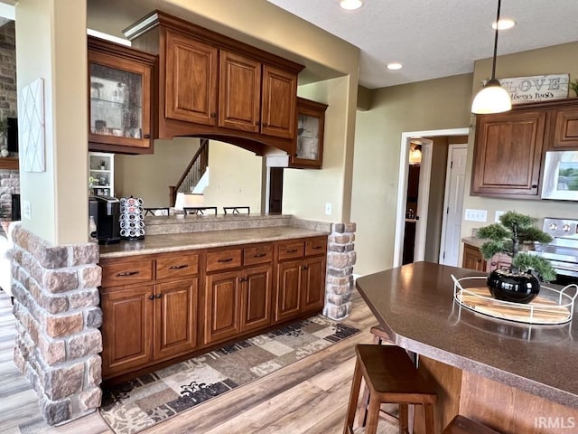 1442 Centerbrook Dr, New Haven, IN 46774 - kitchen featuring white microwave, a kitchen bar, light wood-type flooring, glass insert cabinets, and recessed lighting