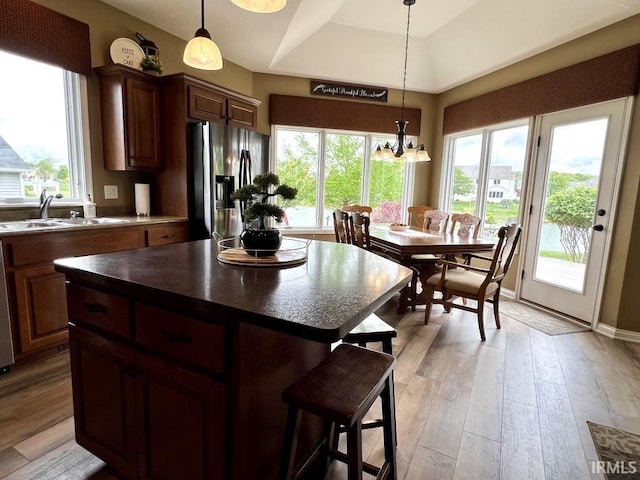 1442 Centerbrook Dr, New Haven, IN 46774 - kitchen featuring stainless steel fridge with ice dispenser, dark countertops, a sink, a kitchen bar, and light wood-style floors