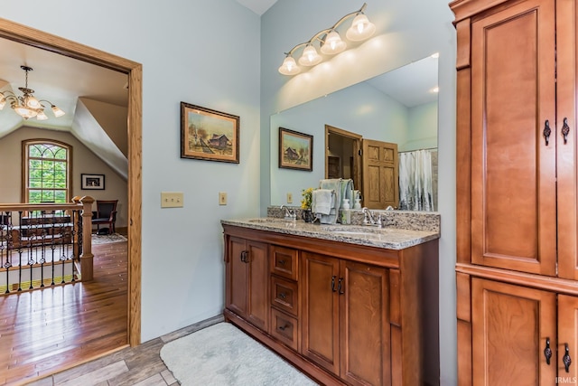 501 W Fox Lake Rd, Angola, IN 46730 - full bath with lofted ceiling, wood finished floors, double vanity, and a chandelier