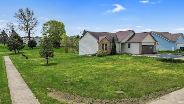 612 E Dunn Rd, New Carlisle, IN 46552 - view of front of house with a trampoline, a garage, a front lawn, and brick siding