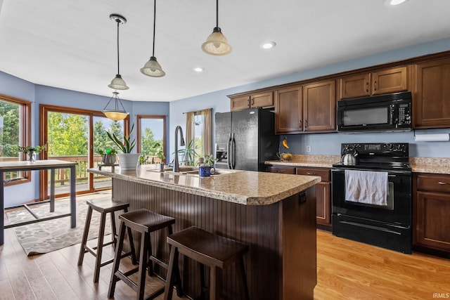 612 E Dunn Rd, New Carlisle, IN 46552 - kitchen featuring black appliances, a sink, light wood-style floors, light countertops, and pendant lighting