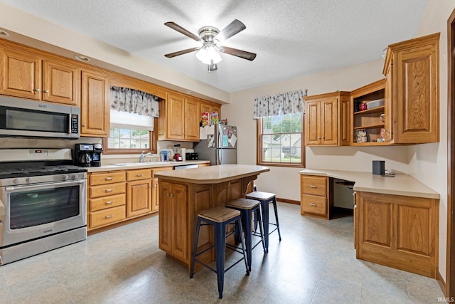517 N Nancy St, Warren, IN 46792 - kitchen with stainless steel appliances, a kitchen breakfast bar, a textured ceiling, a sink, and light countertops