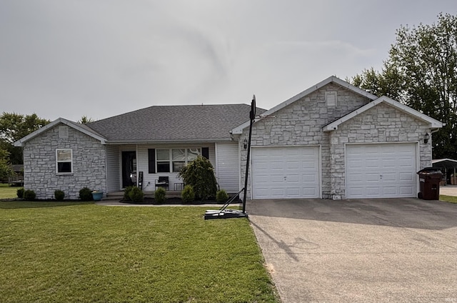 311 Hampshire Dr, Logansport, IN 46947 - ranch-style house with stone siding, a garage, driveway, covered porch, and a front lawn