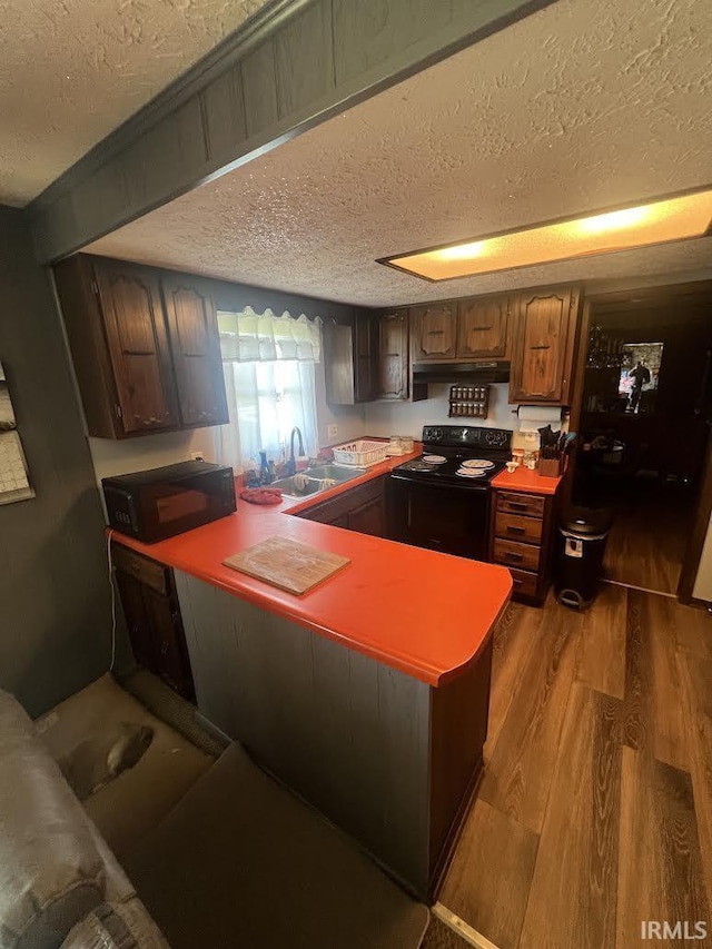 7109 W 100 S, Wabash, IN 46992 - kitchen with black appliances, a textured ceiling, a sink, a peninsula, and wood finished floors